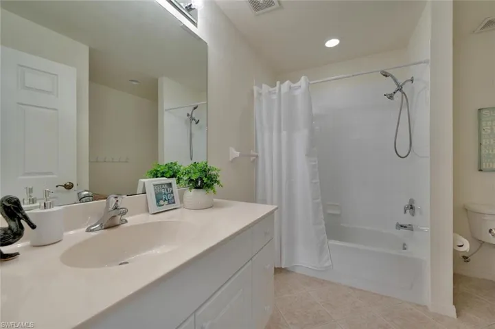 Full bathroom featuring shower / bathtub combination with curtain, tile flooring, toilet, and oversized vanity