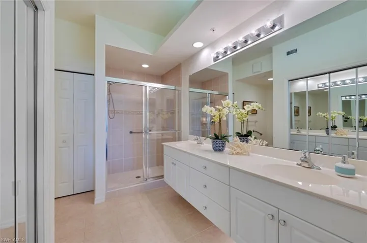 Bathroom featuring tile floors, walk in shower, and double sink vanity