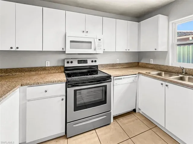 Kitchen featuring white cabinetry, stainless steel range, built-in microwave, dual basin sink, and tile flooring