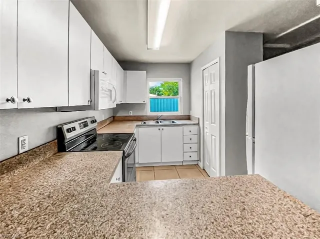 Kitchen featuring white cabinetry, stone-look countertops, and a white appliance package