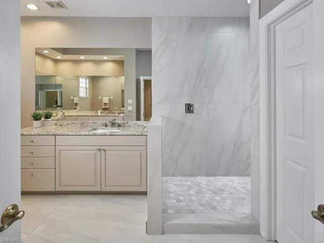 Full bathroom with vanity, a marble finish shower, and recessed lighting