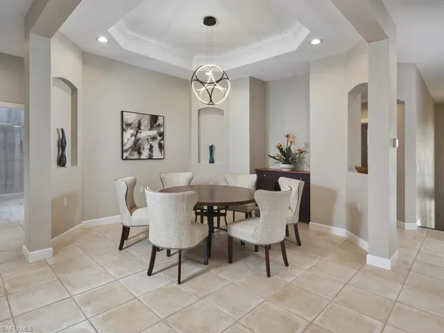Dining room featuring recessed lighting, light tile patterned flooring, crown molding, a raised ceiling, and arched walkways
