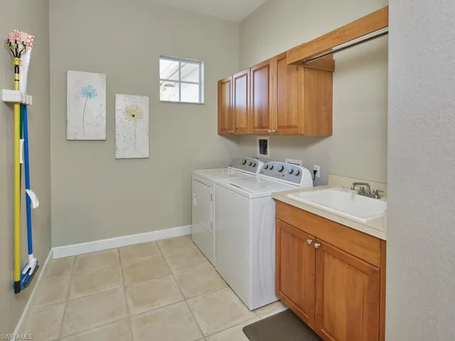 Laundry area with cabinet space, light tile patterned floors, and independent washer and dryer