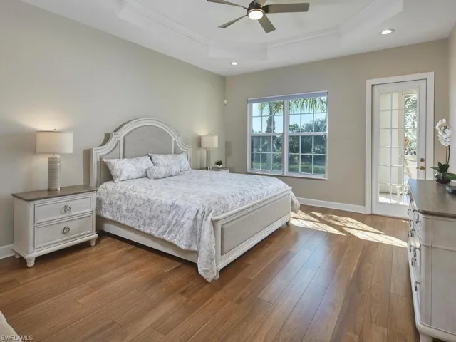 Bedroom featuring a raised ceiling, dark wood-style flooring, crown molding, ceiling fan, and recessed lighting