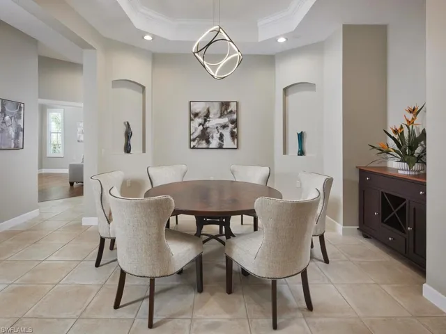 Dining area with ornamental molding, light tile patterned flooring, a raised ceiling, a chandelier, and recessed lighting