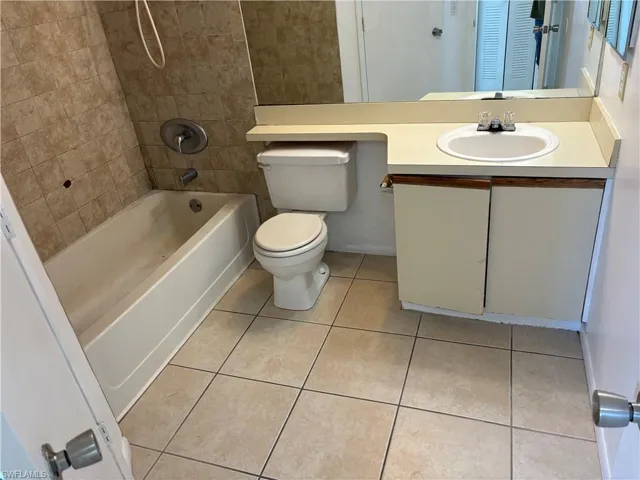 Full bathroom with vanity, tile patterned flooring, tiled shower / bath, and toilet