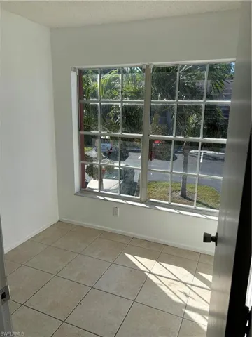 Tiled empty room with a healthy amount of sunlight and a textured ceiling