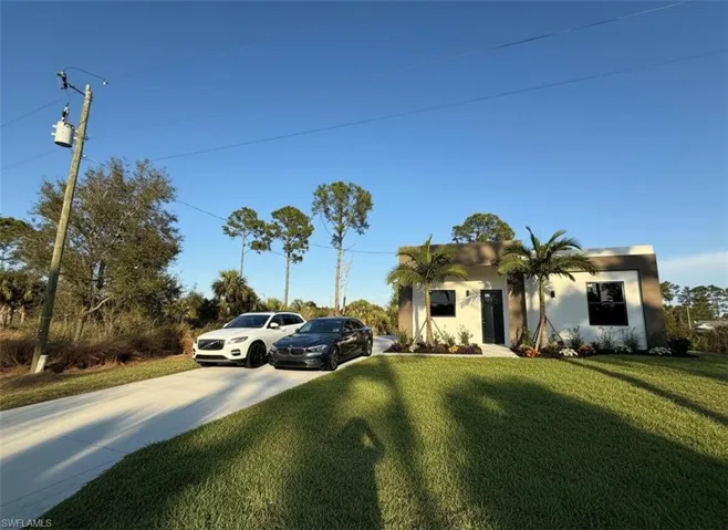 View of front of home with stucco siding, a front lawn, and driveway