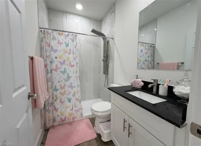 Bathroom featuring a stall shower, vanity, and dark wood finished floors
