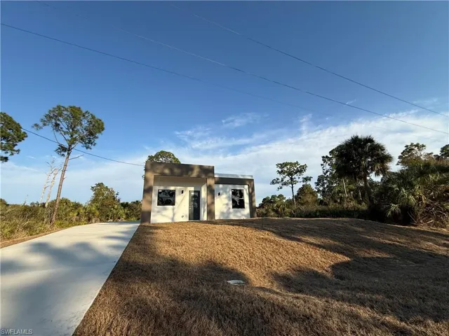 View of front of house featuring stucco siding, an outbuilding, and a front yard