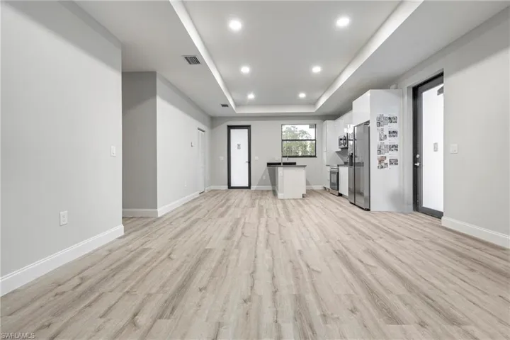 Unfurnished living room with a raised ceiling, light wood-style floors, and recessed lighting