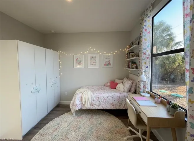 Bedroom with dark wood-style floors and baseboards
