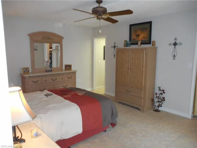 Bedroom featuring a textured ceiling, ceiling fan, and light tile patterned flooring