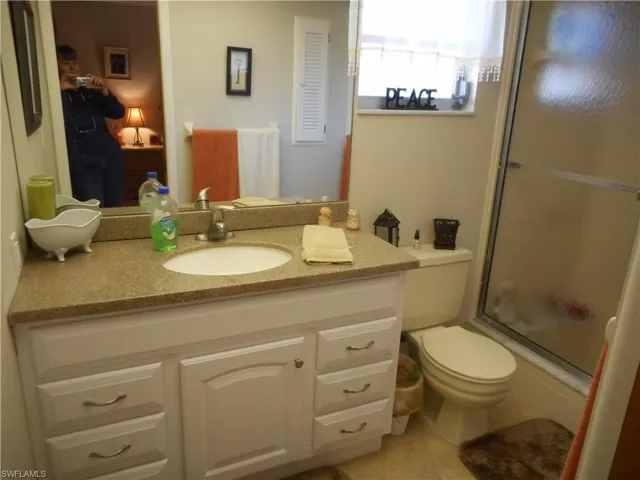 Bathroom featuring vanity, light tile patterned flooring, enclosed tub / shower combo, and connected bathroom