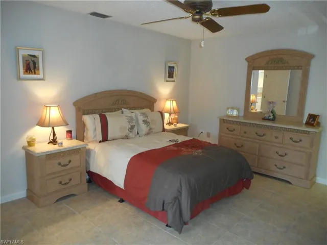 Bedroom featuring a ceiling fan, light tile patterned floors, and a textured ceiling