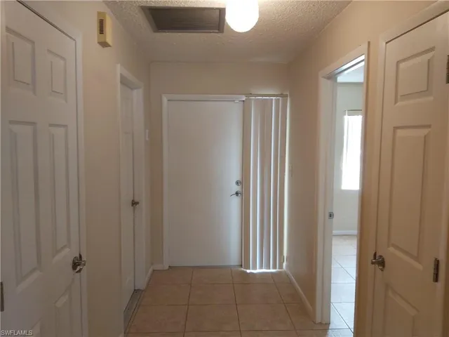 Hallway featuring a textured ceiling and light tile patterned floors