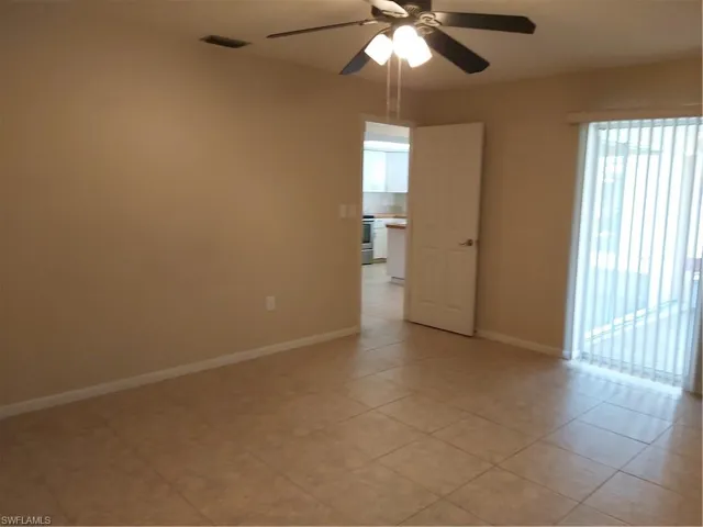 Empty room with a ceiling fan and light tile patterned floors