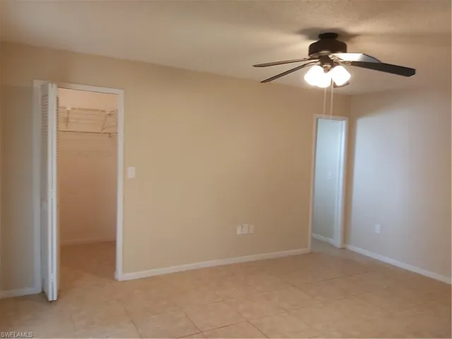 Unfurnished bedroom with a walk in closet and ceiling fan