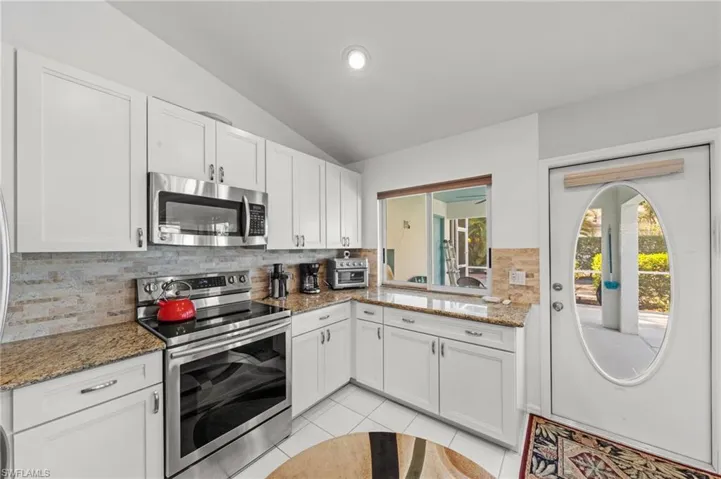 Kitchen featuring white cabinetry, stone-finish countertops, stainless steel appliances, and a tiled backsplash