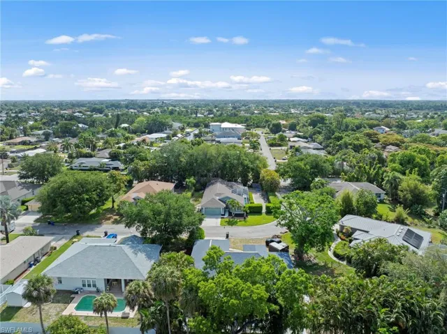 Expansive residential area featuring numerous single-story homes, mature trees, and a clear blue sky overhead