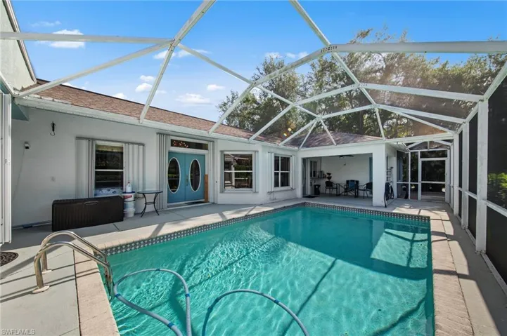 Screened lanai featuring a swimming pool with a step entry, a covered patio area, and direct access to the interior through double-oval-light doors