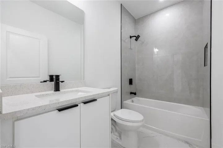 Full bath with vanity, shower / washtub combination, and marble look tiles
