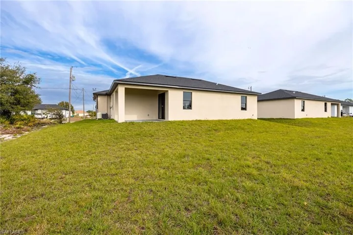 Rear view of property with a yard, stucco siding, and a patio area
