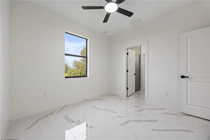 Unfurnished bedroom with ceiling fan and light marble finish floors
