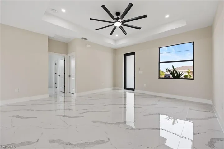 Spare room with ceiling fan, recessed lighting, light marble finish floors, and a raised ceiling