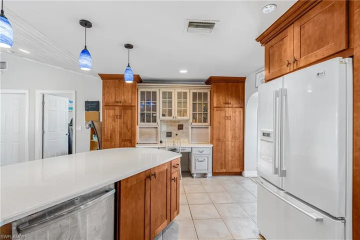 Kitchen with freestanding refrigerator, light countertops, light tile patterned floors, decorative light fixtures, and recessed lighting
