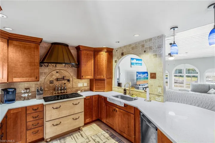 Kitchen featuring premium range hood, black electric cooktop, light countertops, a sink, and open floor plan