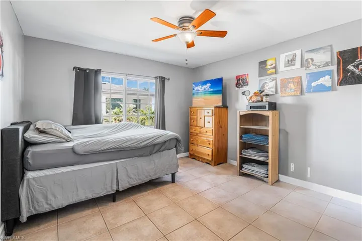 Bedroom featuring light tile patterned flooring, ceiling fan, and baseboards