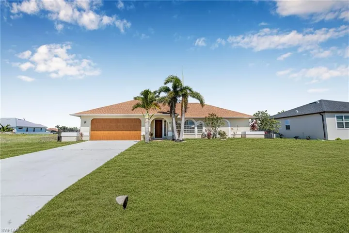 View of front of house featuring concrete driveway, an attached garage, a front lawn, and stucco siding