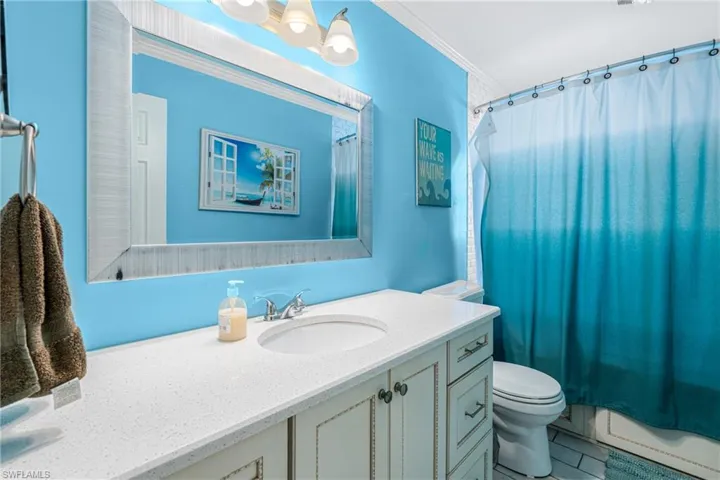 Full bathroom with toilet, vanity, a baseboard radiator, and crown molding