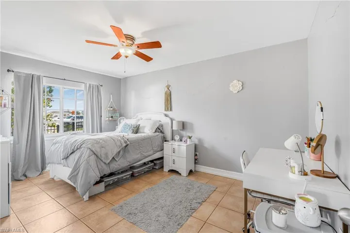Bedroom with light tile patterned flooring, a ceiling fan, and baseboards