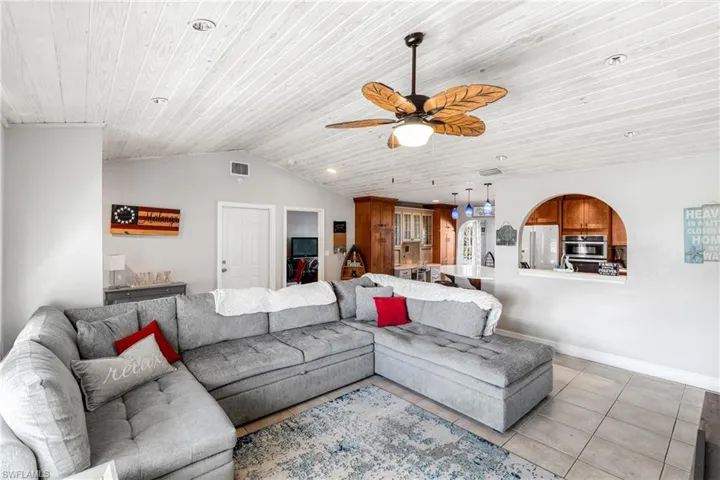Living area with ceiling fan, wooden ceiling, light tile patterned floors, vaulted ceiling, and baseboards