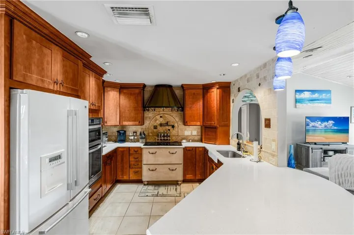 Kitchen with white fridge with ice dispenser, a sink, light tile patterned floors, tasteful backsplash, and light countertops