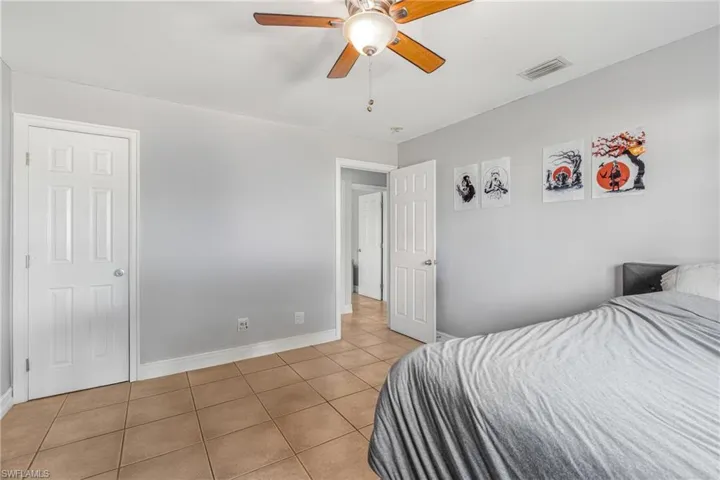 Bedroom with light tile patterned floors, baseboards, and a ceiling fan