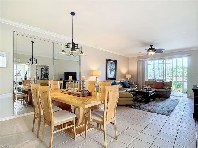 Dining space with ceiling fan with notable chandelier, light tile patterned floors, and crown molding