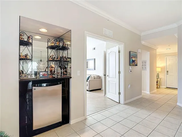 Bar featuring light hardwood / wood-style flooring, crown molding, and refrigerator