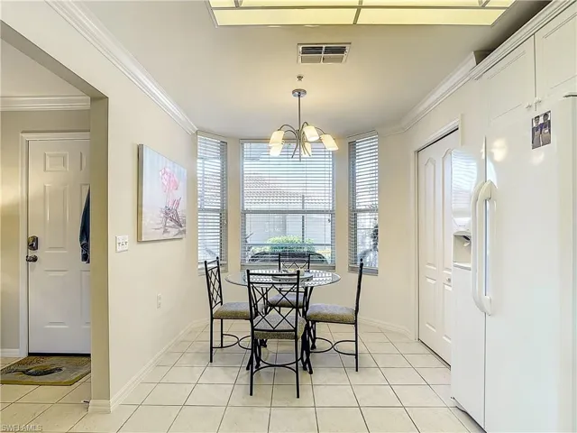 Tiled dining space featuring a notable chandelier and crown molding