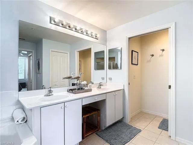 Bathroom featuring shower with separate bathtub, tile patterned flooring, and dual vanity