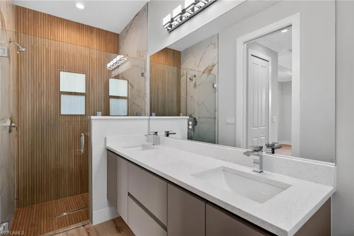 Dual-sink floating vanity with quartz countertops, chrome fixtures, and a large wall-mounted mirror