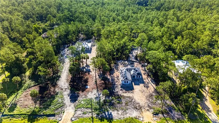 Aerial view of multiple properties under construction, surrounded by extensive mature trees