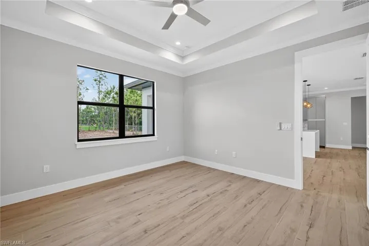 Spacious room featuring wood-finish flooring, a coffered ceiling with recessed lighting and a ceiling fan, and a large window with black framing