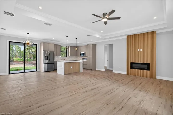 Spacious living area featuring wood-finish flooring, a modern electric fireplace with a slatted wood accent wall, and recessed lighting