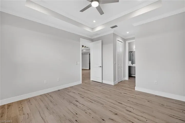 Spacious room with wood-finish flooring, light grey wall tones, and white crown molding