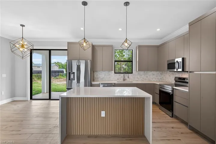 Modern kitchen featuring a waterfall island with fluted paneling, light wood-finish flooring, and recessed lighting
