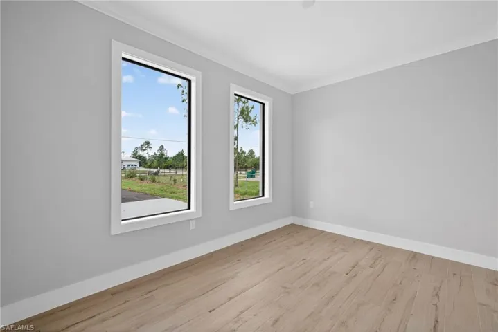 Room featuring light gray walls, wood-finish flooring, and white baseboards
