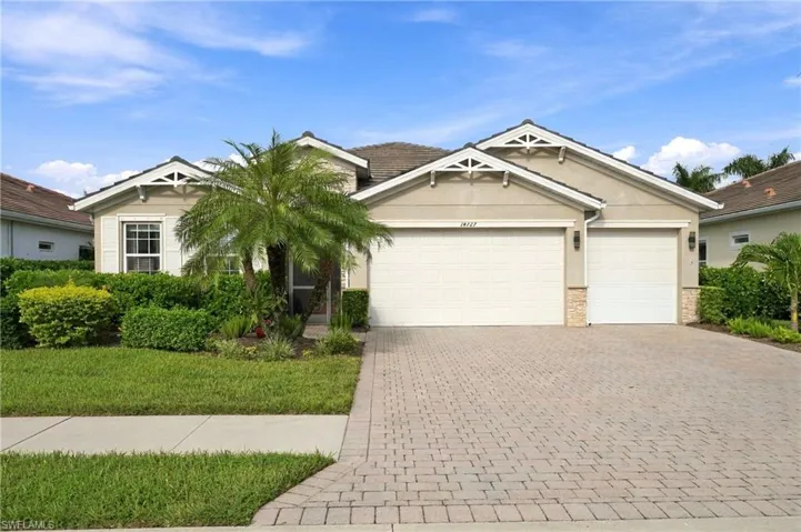 Single-story exterior featuring a paver driveway, three-car garage, gable rooflines with decorative brackets, and stone veneer accents